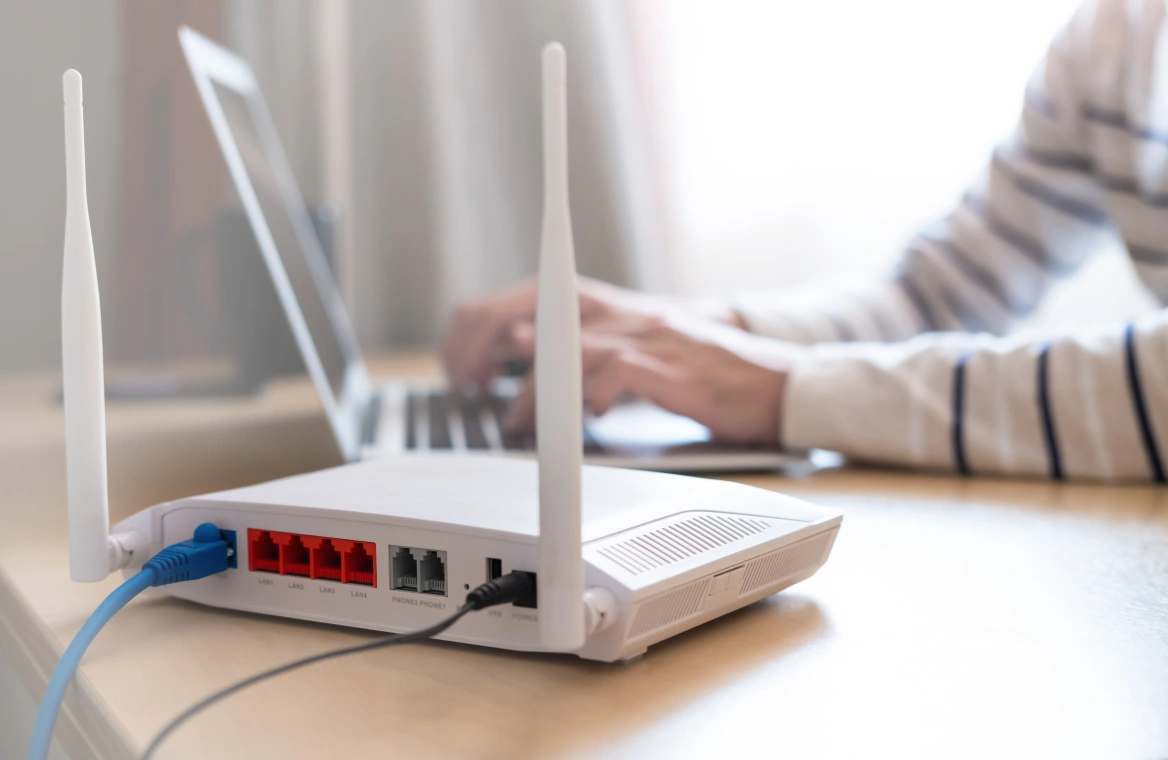 A router sitting on a desk and a person using a laptop
