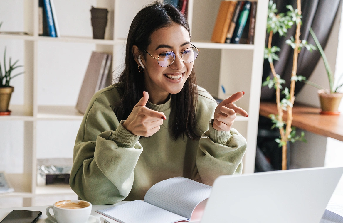 A woman in an office space with plants and books uses her laptop