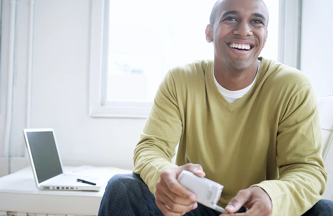 A man with a laptop and cellphone connected to Wi-Fi at home